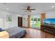 Spacious bedroom with a ceiling fan, hardwood floors, and a TV, featuring a view of the yard at 5500 State Road 33, Clermont, FL 34714
