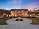 Elegant two-story home featuring a circular driveway, stone accents, and lush landscaping at twilight at 5500 State Road 33, Clermont, FL 34714