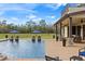 A large swimming pool with seating areas, umbrellas, and a covered porch overlooks a lush green lawn at 5500 State Road 33, Clermont, FL 34714