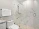Modern bathroom featuring a glass shower with marble tile surround, a sleek rain shower head, and a toilet with stacked white towels at 5950 Masters Blvd, Orlando, FL 32819