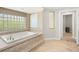 Bathroom featuring a luxurious soaking tub with tile surround and a glass block window at 5950 Masters Blvd, Orlando, FL 32819