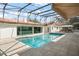A private in-ground pool surrounded by a tile deck and screened enclosure has an awning, seating, and poolhouse with kitchen at 5950 Masters Blvd, Orlando, FL 32819