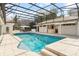 A beautiful private pool is encased in a screened enclosure with a tile pool deck, seating, and a covered outdoor kitchen at 5950 Masters Blvd, Orlando, FL 32819
