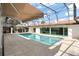 An in-ground pool in a screened in enclosure is surrounded by a tile pool deck and has an awning for shade at 5950 Masters Blvd, Orlando, FL 32819