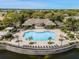Aerial view of a large community pool surrounded by lounge chairs and lush landscaping and a nearby pond at 6451 Old Park Ln # 302, Orlando, FL 32835