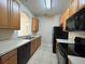 Kitchen with wood cabinetry, black appliances, and ample counter space at 6451 Old Park Ln # 302, Orlando, FL 32835