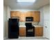 Kitchen featuring wood cabinets, black appliances, and ample counter space at 6451 Old Park Ln # 302, Orlando, FL 32835