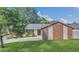 View of a well maintained single story home with green lawn and mature trees with a brick accented bump-out at 7325 Burnway Dr, Orlando, FL 32819
