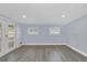 Bright living room with gray wood-look floors, white trim, and natural light from the glass paneled doors and two windows at 7325 Burnway Dr, Orlando, FL 32819