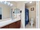 Bright bathroom featuring a single sink vanity with a large mirror and a separate toilet area with a shower at 877 Scrub Jay Way, Davenport, FL 33896