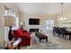 Sunlit living room features a red sofa, electric fireplace, and adjacent dining area with modern chandelier at 877 Scrub Jay Way, Davenport, FL 33896