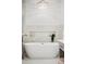 Soaking tub situated below a chandelier in neutral colored bathroom at 900 Golfview St, Orlando, FL 32804