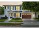 Charming two-story home featuring a blue door, well-maintained landscaping, and a two-car garage at 900 Golfview St, Orlando, FL 32804