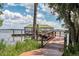 Wooden dock with a covered pavilion on a peaceful lake, framed by lush greenery at 10078 Greenshire Way, Orlando, FL 32827