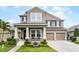 Charming two-story home with landscaped yard and a two-car garage under a bright blue sky at 10078 Greenshire Way, Orlando, FL 32827