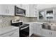 Kitchen with stainless steel appliances, white cabinets, and a mosaic tile backsplash at 1070 Lake Ariana Blvd, Auburndale, FL 33823