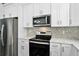 Bright kitchen featuring stainless steel appliances, white cabinets, and mosaic backsplash at 1070 Lake Ariana Blvd, Auburndale, FL 33823