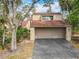 Beige two-story home featuring an attached two-car garage, asphalt driveway, and mature landscaping at 117 Starling Ln, Longwood, FL 32779