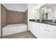 Bathroom featuring soaking tub with tiled walls, dual sinks, and granite counters at 150 E Robinson St # 2308, Orlando, FL 32801