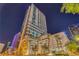 Elegant high-rise condo building with a sleek design and palm tree landscaping at nighttime at 150 E Robinson St # 2308, Orlando, FL 32801