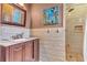 Bathroom with a shower, light brown and white tiled walls, brown cabinetry and marble counter at 1943 Wingfield Dr, Longwood, FL 32779