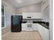 Well-lit kitchen with white cabinetry, black countertops, and stainless steel appliances at 2808 Osprey Cove Pl # 202, Kissimmee, FL 34746