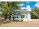 Charming single-story home with white exterior, surrounded by lush trees and mature landscaping at 4840 Transport Rd, Bartow, FL 33830