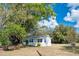 Quaint single-story home with a white exterior, nestled amid mature trees and expansive grassy area at 4840 Transport Rd, Bartow, FL 33830