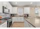 Bright kitchen with white cabinets, stainless steel appliances and modern fixtures and tile backsplash at 5058 Sparkling Water Way, Kissimmee, FL 34746