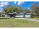 Rear view of cozy single-story home with covered carport and spacious grassy yard at 519 Pearl St, Mascotte, FL 34753