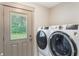 Modern laundry room with high efficiency washer and dryer next to a windowed door at 598 Palm Dr, Oviedo, FL 32765