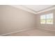 Neutral-toned bedroom features a tray ceiling, a large window, and neutral carpet at 6097 Monterey Cypress Trl, Sanford, FL 32773