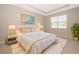 Comfortable main bedroom features a tray ceiling, a large window, and neutral decor at 6097 Monterey Cypress Trl, Sanford, FL 32773