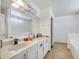 Bright bathroom featuring a double vanity with white cabinets and a large mirror and tiled floor at 639 Mesilla Dr, Kissimmee, FL 34758
