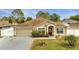 Exterior view of a charming home with an attached garage, red door, manicured lawn, and mature trees at 639 Mesilla Dr, Kissimmee, FL 34758