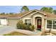 Charming single-story home with a well-manicured lawn, attached garage, and inviting red front door at 639 Mesilla Dr, Kissimmee, FL 34758