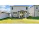 Back view of the home with a covered patio, grassy yard, and grey siding at 869 Rivers Crossing St, Clermont, FL 34714