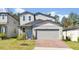 Charming two-story home featuring gray siding, a brick driveway, and a light blue front door at 869 Rivers Crossing St, Clermont, FL 34714