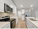Well-lit kitchen boasts stainless steel appliances and island with a sink and white cabinets at 869 Rivers Crossing St, Clermont, FL 34714