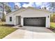 Charming single-story home showcasing a well-manicured lawn and a dark two car garage door at 12380 Sw 71St Lane Rd, Ocala, FL 34481
