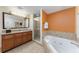 Bathroom with a soaking tub, walk-in shower, and vanity with a large mirror and wooden cabinets at 12527 Floridays Resort Dr # 401E, Orlando, FL 32821