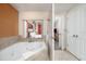 Bright bathroom with a soaking tub and a pass-through window offering a glimpse into the adjacent bedroom at 12527 Floridays Resort Dr # 401E, Orlando, FL 32821
