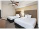 Cozy bedroom with two beds, soft lighting, and a ceiling fan at 12527 Floridays Resort Dr # 401E, Orlando, FL 32821