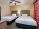 Comfortable bedroom featuring two beds, ceiling fan, and warm inviting decor at 12527 Floridays Resort Dr # 401E, Orlando, FL 32821