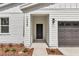 This is a close up of the home's entryway with a black door, modern lighting, and manicured landscaping at 12639 Sw 78Th Pl, Dunnellon, FL 34432