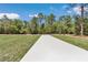 Long concrete driveway leading to the property, surrounded by lush greenery and trees at 13274 Sw 82Nd Ln, Dunnellon, FL 34432