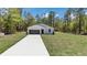 New home with a bright white exterior, lush green lawn, and a long concrete driveway at 13274 Sw 82Nd Ln, Dunnellon, FL 34432