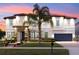 Elegant two-story home with lush landscaping, a tile roof, and a stone-accented facade at dusk at 19313 Pummelo Dr, Orlando, FL 32827