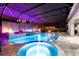 A view of the swimming pool and hot tub with screened enclosure under violet accent lights at 19313 Pummelo Dr, Orlando, FL 32827