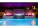 An in-ground pool with a waterfall feature and a geometric patterned backsplash under violet lighting at 19313 Pummelo Dr, Orlando, FL 32827
